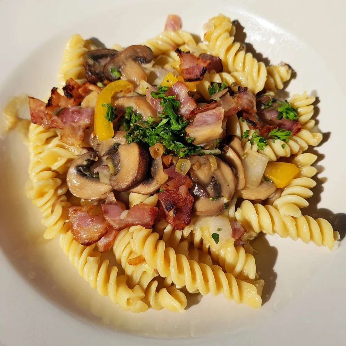 Tempting fusilli with bacon, onions, and mushrooms: garnished with fresh parsley and Parmesan.