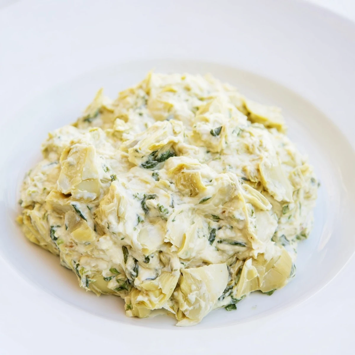 A bubbling baking dish filled with rich spinach artichoke dip, perfect for sharing at a gathering.