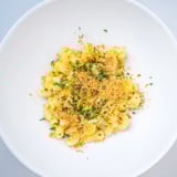 A steaming bowl of Curry Comfort Mac and Cheese, topped with golden breadcrumbs and fresh herbs.