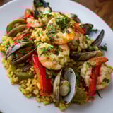 Bright red bell peppers and fresh parsley garnish this beautiful, gluten-free Spanish seafood paella dish.