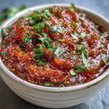 A vibrant bowl of Guava Chutney featuring bright pink puree, finished with a golden mustard seed and curry leaf tempering.