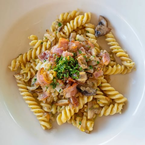 Savory fusilli with bacon, onions, and mushrooms: a close-up of the delicious pasta.