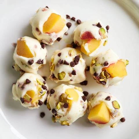 Frozen peach yogurt bites, creamy and speckled with diced peaches, ready to be enjoyed as a cool treat.
