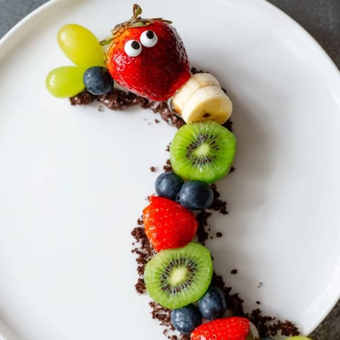 A delicious view: Kids' Caterpillar Fruit Skewer Track with juicy fruit arranged like whimsical caterpillars.