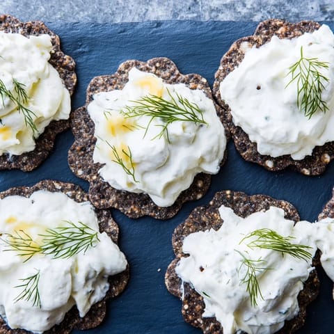 Delicious The Stormy Sea appetizer: creamy goat cheese swirls atop dark crackers on a blue slate.