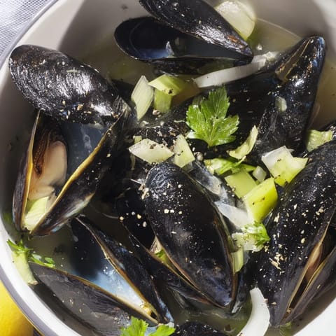 A photo showcasing a steaming pot of Belgian Moules Marinière with aromatic white wine and savory broth.