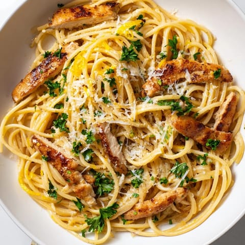 Close-up of a warm plate of brown butter lemon chicken pasta garnished with parsley, showcasing glossy sauce and tender seared chicken strips.