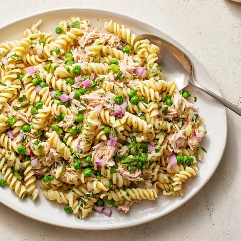 Fork-ready Lemony Tuna Pasta Salad features vibrant red onion and dill, perfect for an easy spring lunch or picnic meal.  