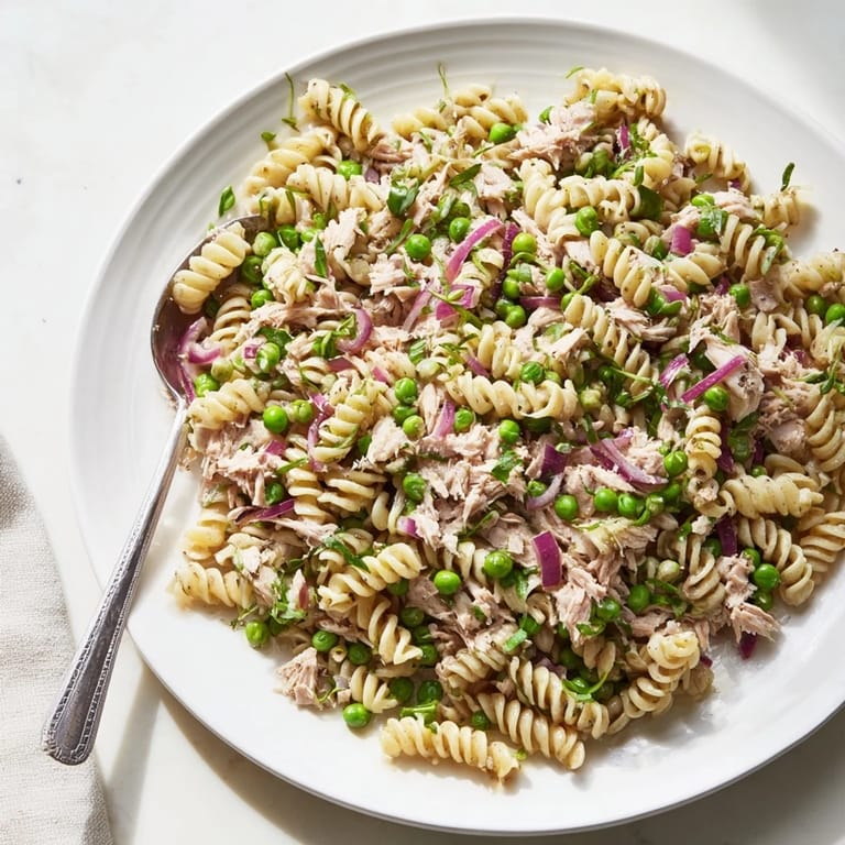 A refreshing Lemony Tuna Pasta Salad served chilled, garnished with chopped parsley and lemon zest for a zesty finish.