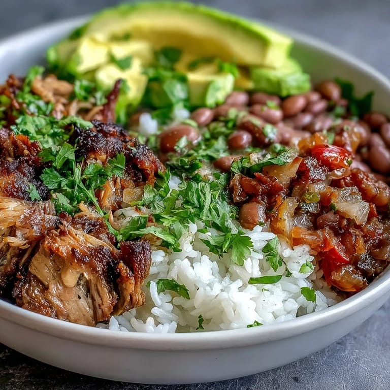 A hearty Carnitas Bowl with slow-cooked pork, fluffy rice, and vibrant toppings like fresh salsa and sliced avocado.