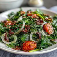 Bright dandelion greens salad with cherry tomatoes, red onion, and Parmesan, tossed in zesty lemon vinaigrette for a fresh Mediterranean dish.