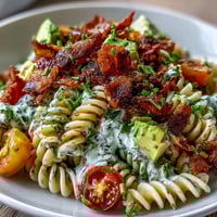 A colorful bowl of BLT Pasta with Avocado Ranch, featuring crispy bacon, juicy tomatoes, and fresh lettuce in a creamy dressing.